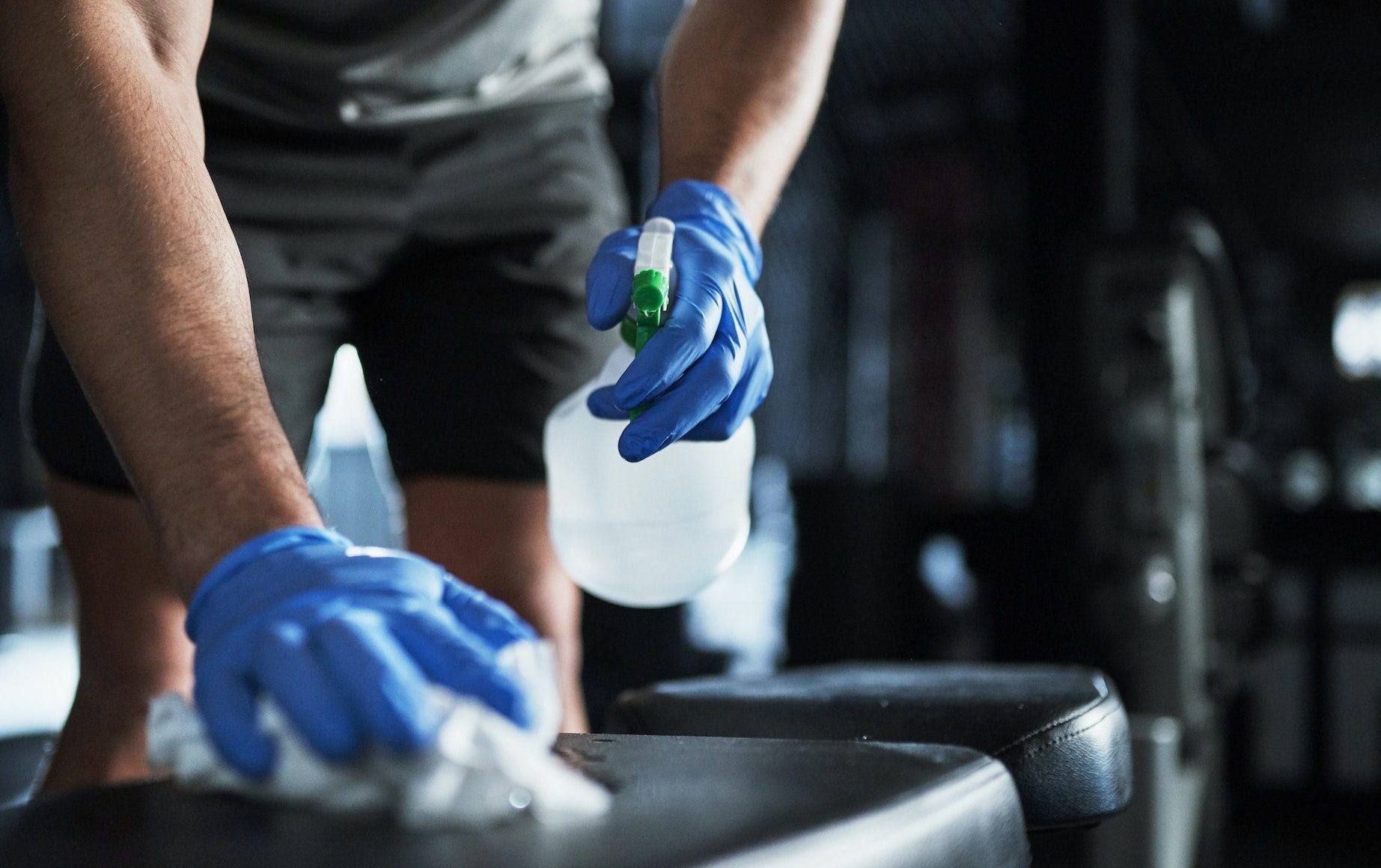 Cropped shot of an unrecognisable man disinfecting the surfaces in a gym